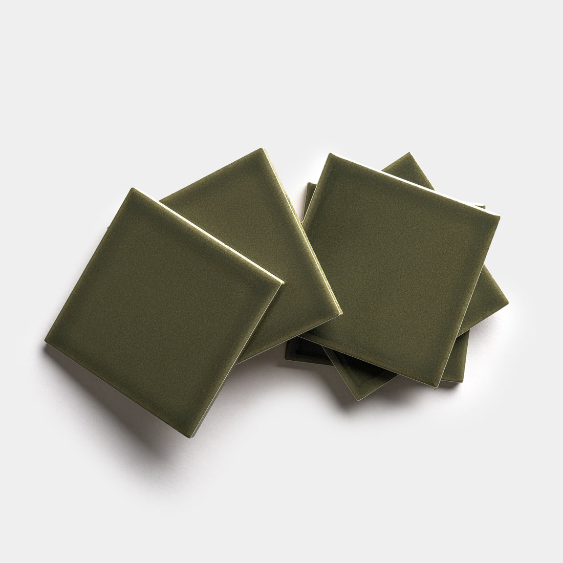 Six Vetiver 4x4 olive green square ceramic tiles by Zia Tile are stacked and slightly overlapping on a plain white background.
