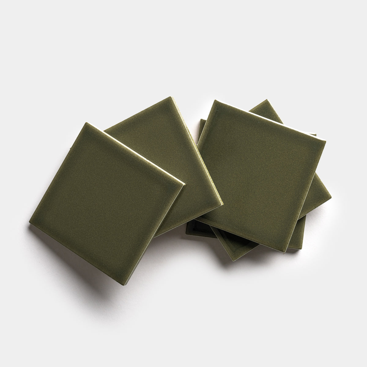 Six Vetiver 4x4 olive green square ceramic tiles by Zia Tile are stacked and slightly overlapping on a plain white background.