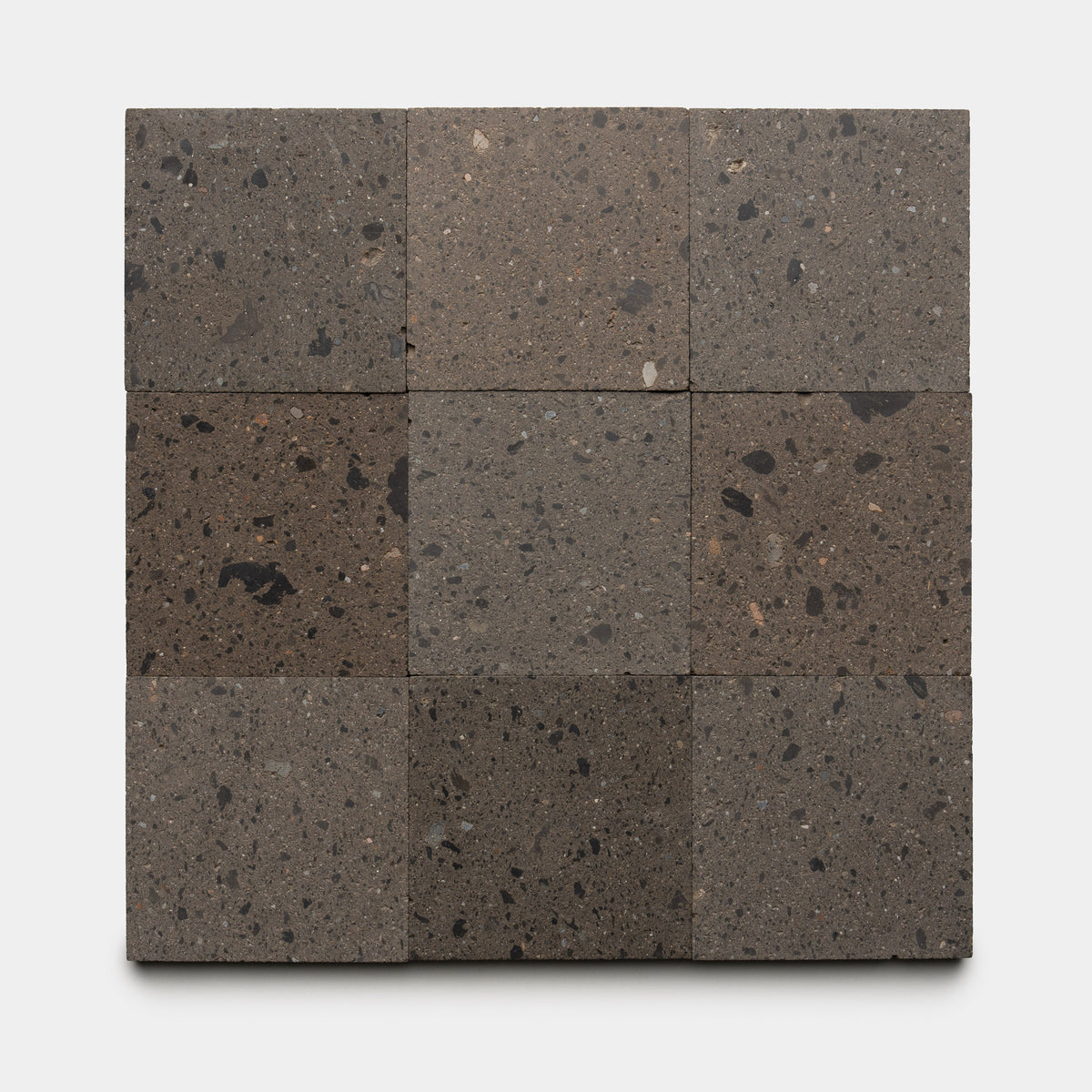Nine Volcan 6x6 tiles by Zia Tile are arranged in a 3x3 grid on a light background. The dark, speckled cantera tiles feature a rough texture with visible aggregates, highlighting the distinctive character of this natural material.