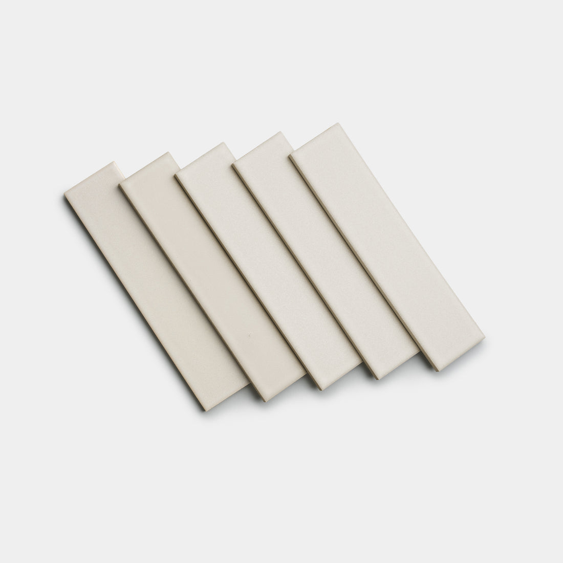 Five rectangular, cream-colored Wool 2x8 tiles from Zia Tile are arranged in a slightly overlapping, fanned-out pattern on a plain white background.