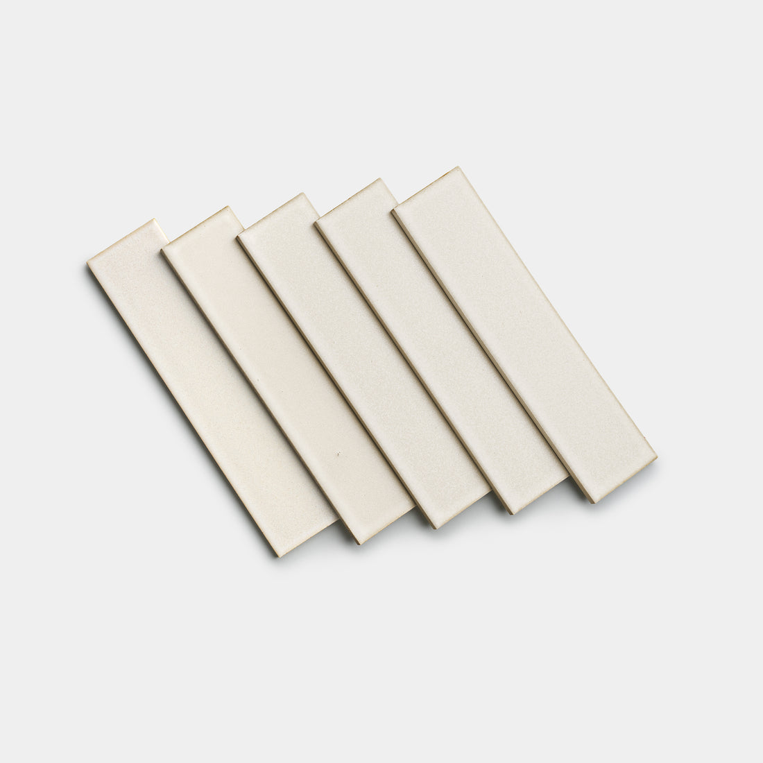 Five Wool 2x8 rectangular tiles by Zia Tile in light beige are arranged in a slightly overlapping, diagonal pattern on a plain white background.