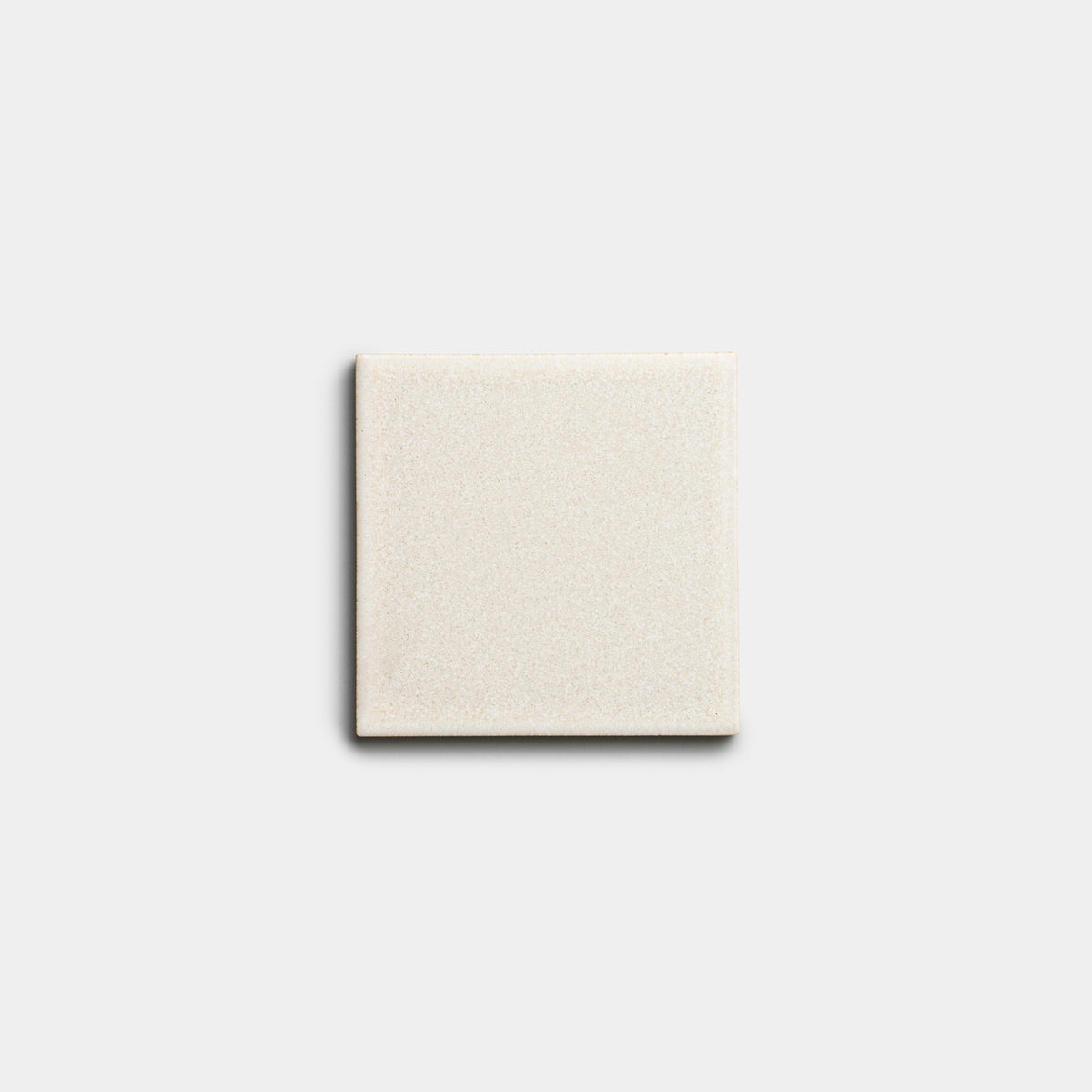 A single Wool 4x4 sample tile by Zia Tile, in light beige ceramic and square shape, is centered on a plain, light gray background.