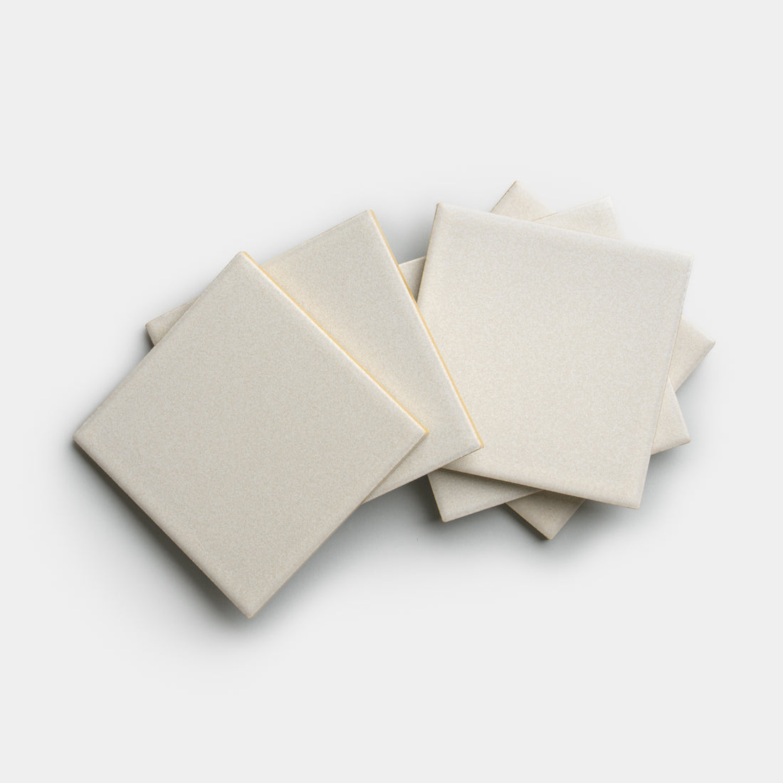 Five square Wool 4x4 ceramic tiles by Zia Tile, cream-colored and slightly overlapping, are arranged on a plain white background.