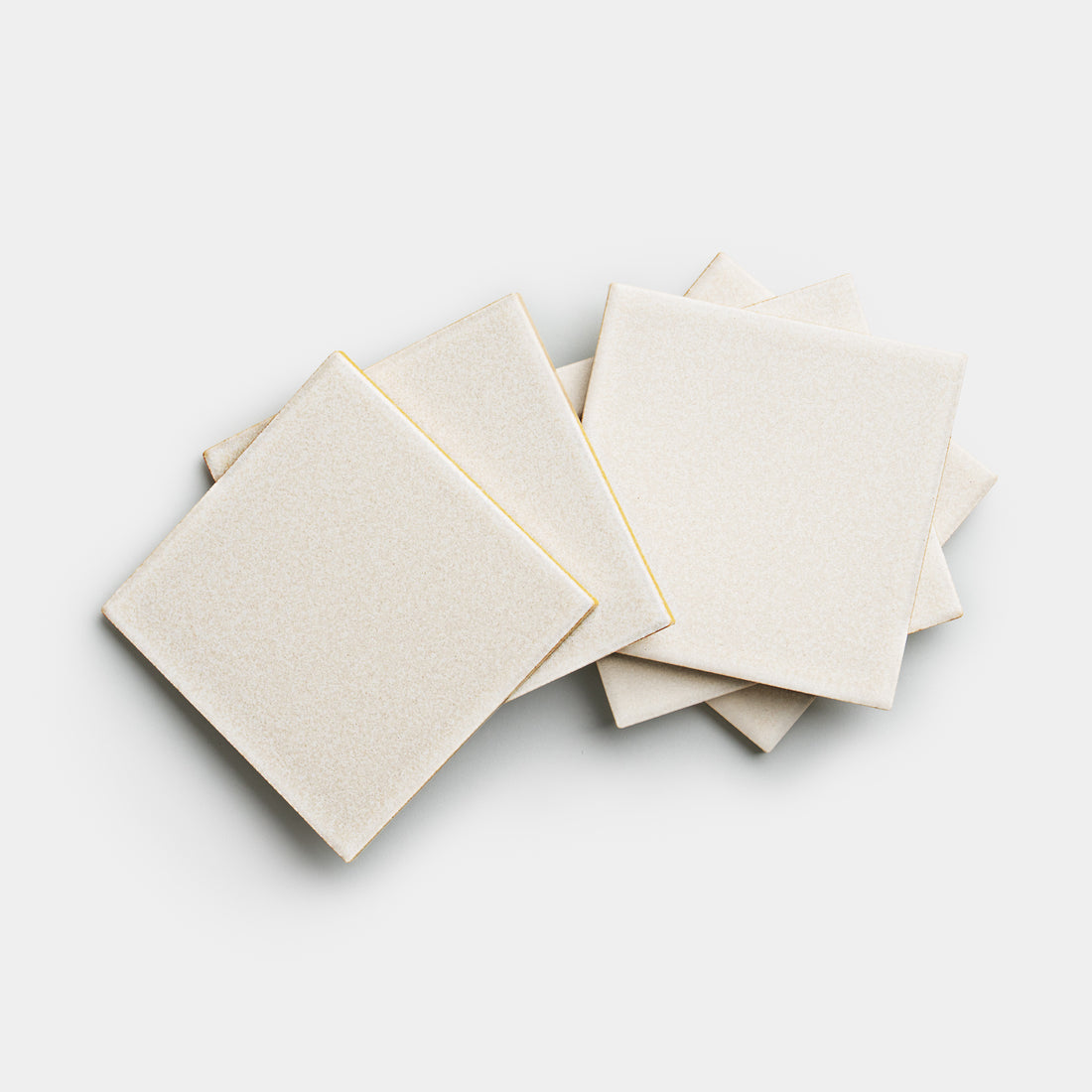 Five Wool 4x4 ceramic tiles by Zia Tile are shown in a slightly scattered stack, square and beige, on a white background.