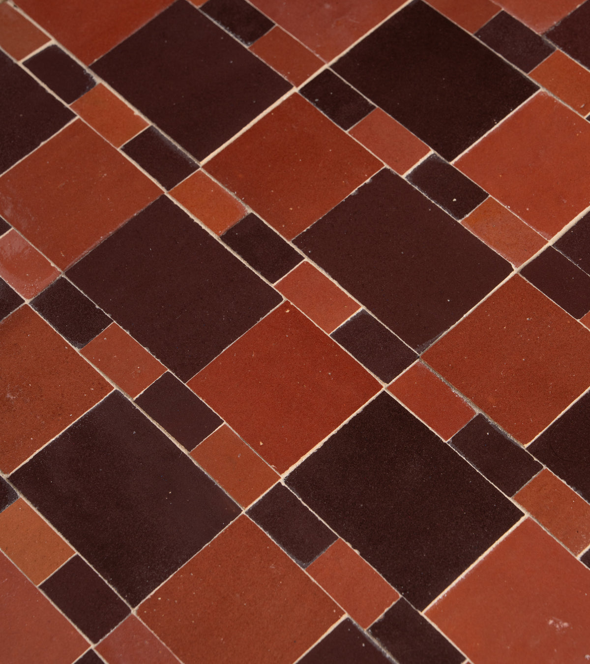 A close-up of Zia Tile’s Xylem 1, showcasing an abstract geometric surface with red and dark brown rectangles and squares arranged in an irregular grid.