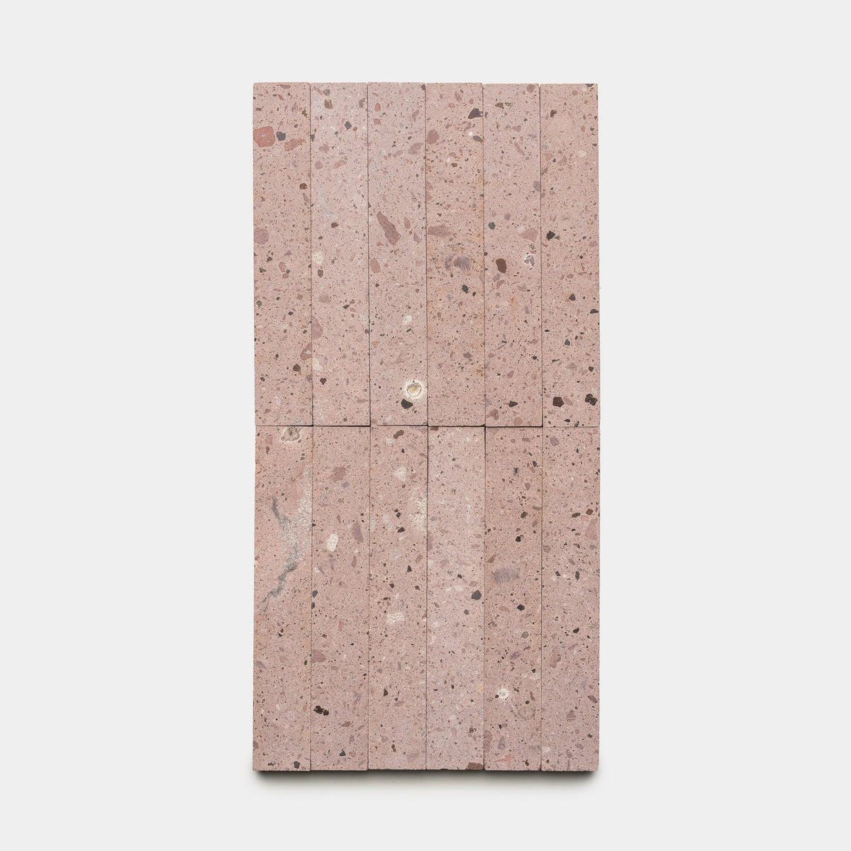 Yuma 2x12 by Zia Tile features a rectangular layout of pinkish stone tiles with natural speckles and textures, arranged vertically in a grid on a plain white background.