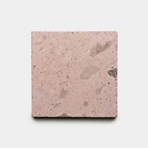 The Yuma 6x6 by Zia Tile is a square tile featuring a pinkish hue, rough texture, and specks of lighter and darker colors, displayed on a plain white background.