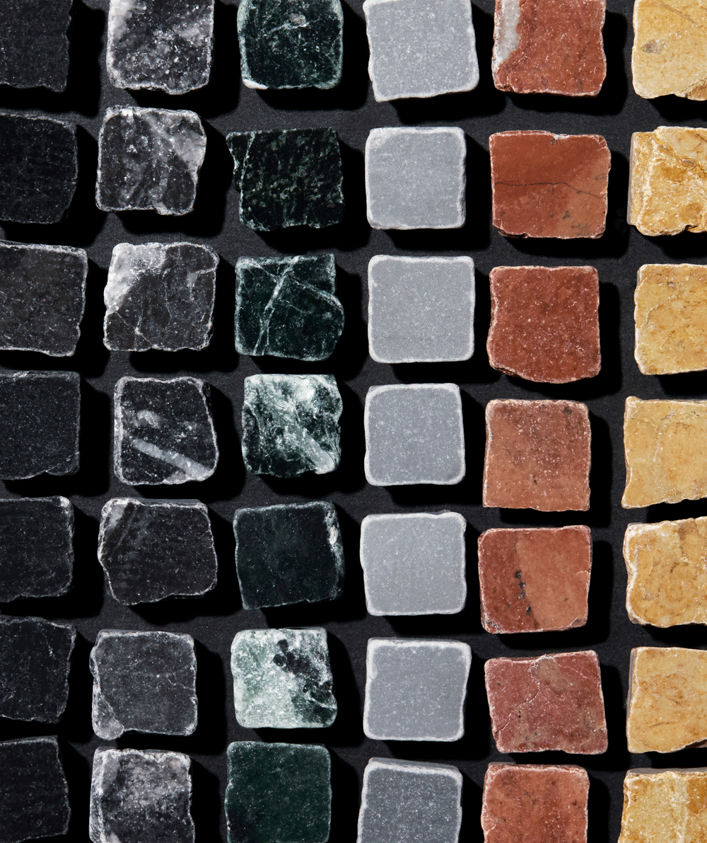 A grid of square stone tiles in various colors—black, dark green, gray, red, and yellow—arranged in neat rows and columns on a dark background.