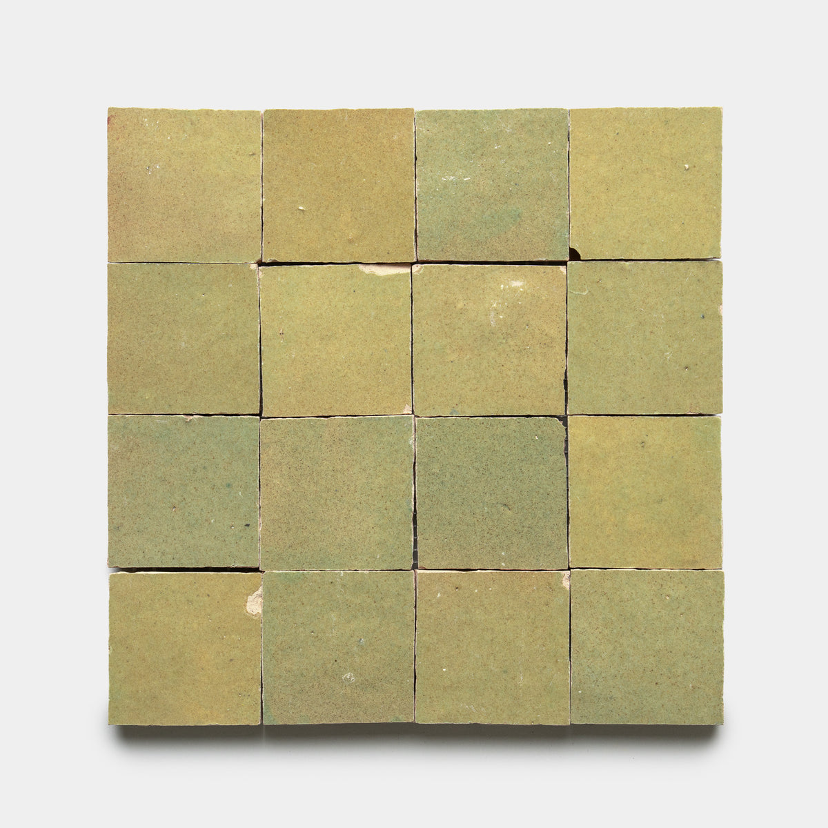 A square grid of 16 Za'atar 2x2 green ceramic tiles by Zia Tile, matte finish with some chips and surface imperfections, arranged evenly on a plain white background.