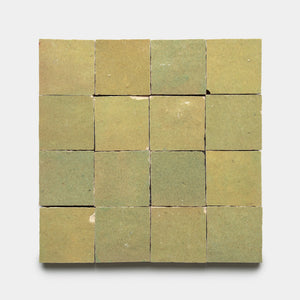 A square grid of 16 Za'atar 2x2 green ceramic tiles by Zia Tile, matte finish with some chips and surface imperfections, arranged evenly on a plain white background.