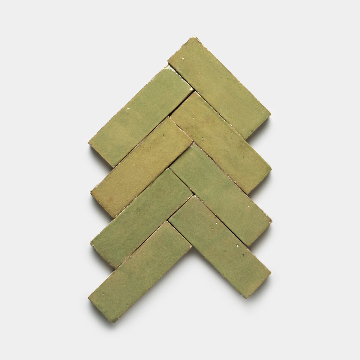 Eight Za'atar 2x6 green tiles from Zia Tile are arranged in a herringbone pattern on a plain white background.
