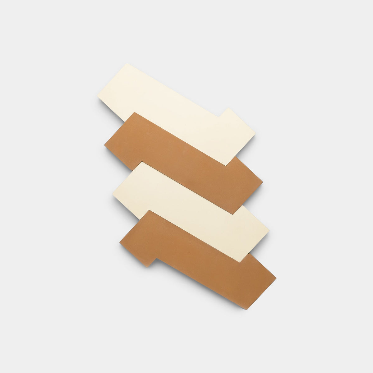 Four rectangular Zig Zag Bone + Saddle samples from Zia Tile—two cream, two brown—are arranged in an alternating, staggered pattern on a plain light gray background, highlighting the brand’s artisanal handmade craftsmanship.