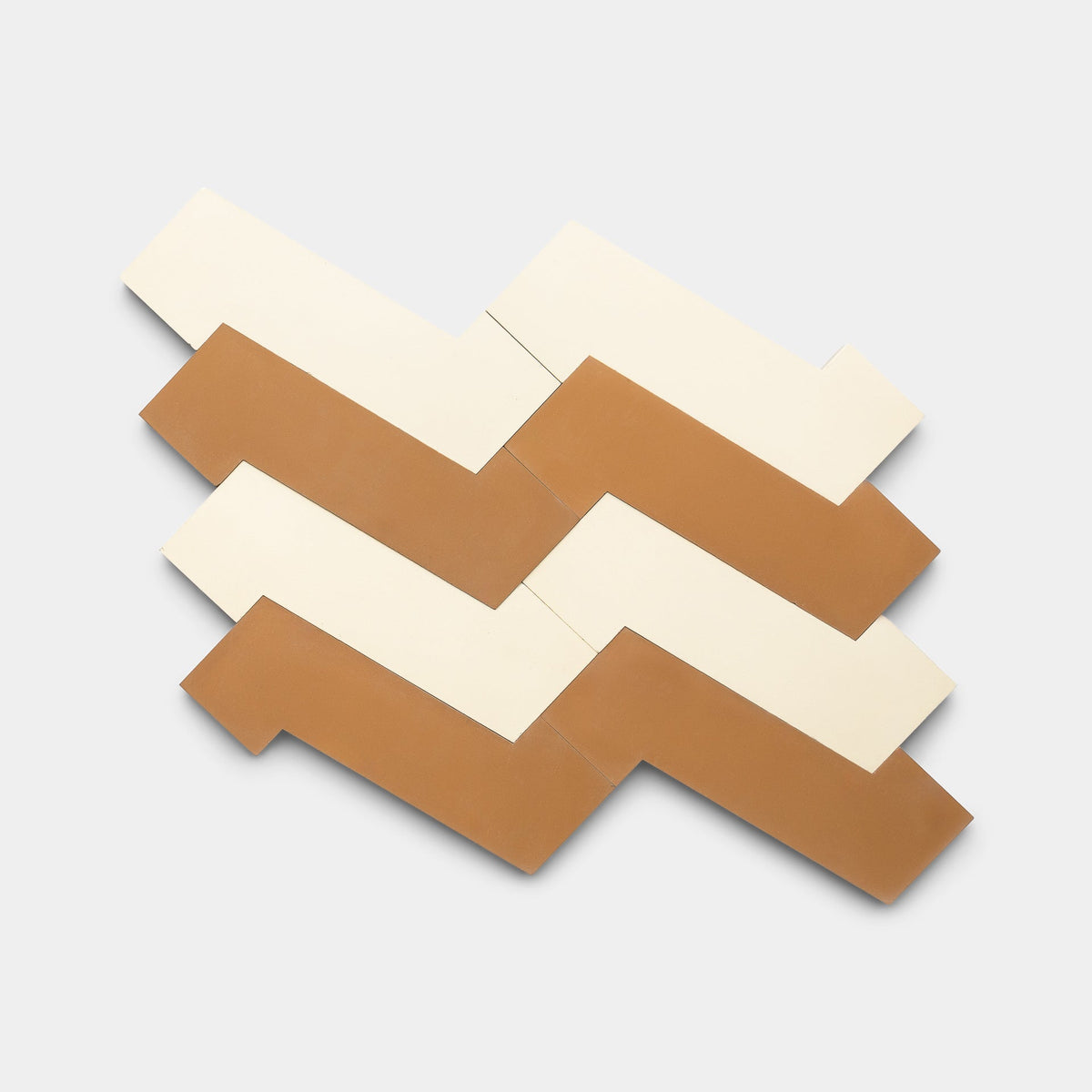 Zig Zag Bone + Saddle by Zia Tile features four interlocking geometric cement tiles in cream and terracotta, arranged in a zigzag pattern on light gray. Each handmade rectangular tile has an angled cutout on one side.