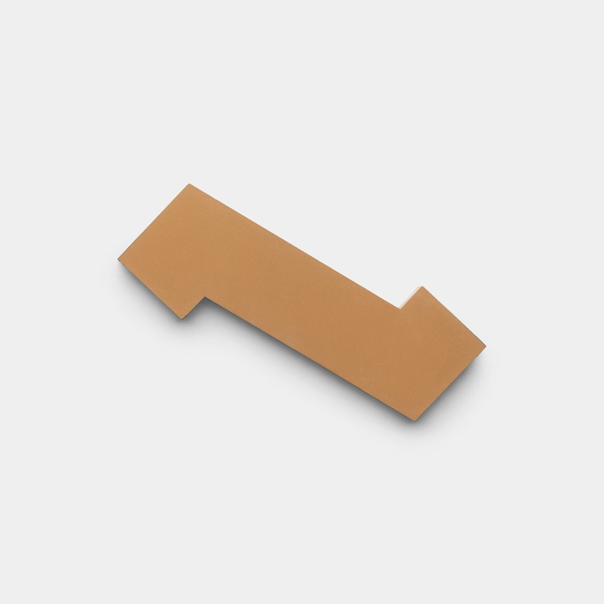A single Zig Zag Bone + Saddle tile sample by Zia Tile, flat and irregularly shaped with a brown hue, is centered against a plain white background.