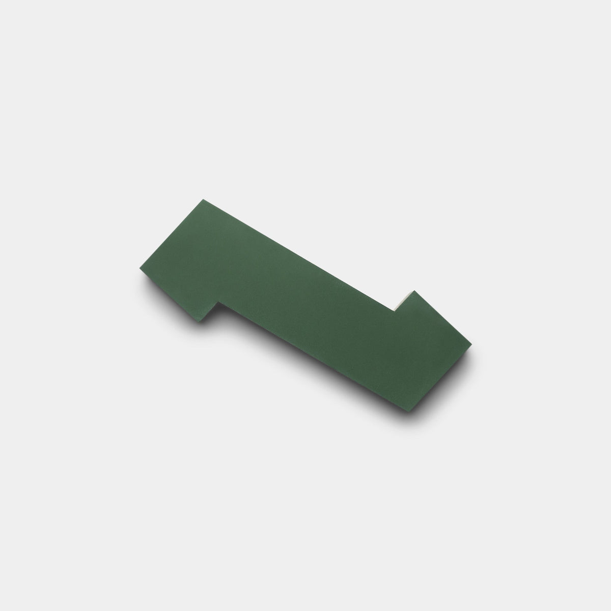 The Zig Zag Hailstone + Noble Green sample by Zia Tile is a flat, solid green geometric tile with sharp angles and a small rectangular notch, shown on a plain light gray background.