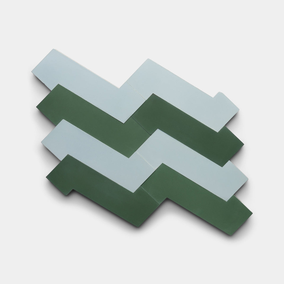 Five interlocking Zia Tile “Zig Zag Hailstone + Noble Green” sample tiles with zigzag edges—alternating light blue and dark green—are arranged on a plain white background.