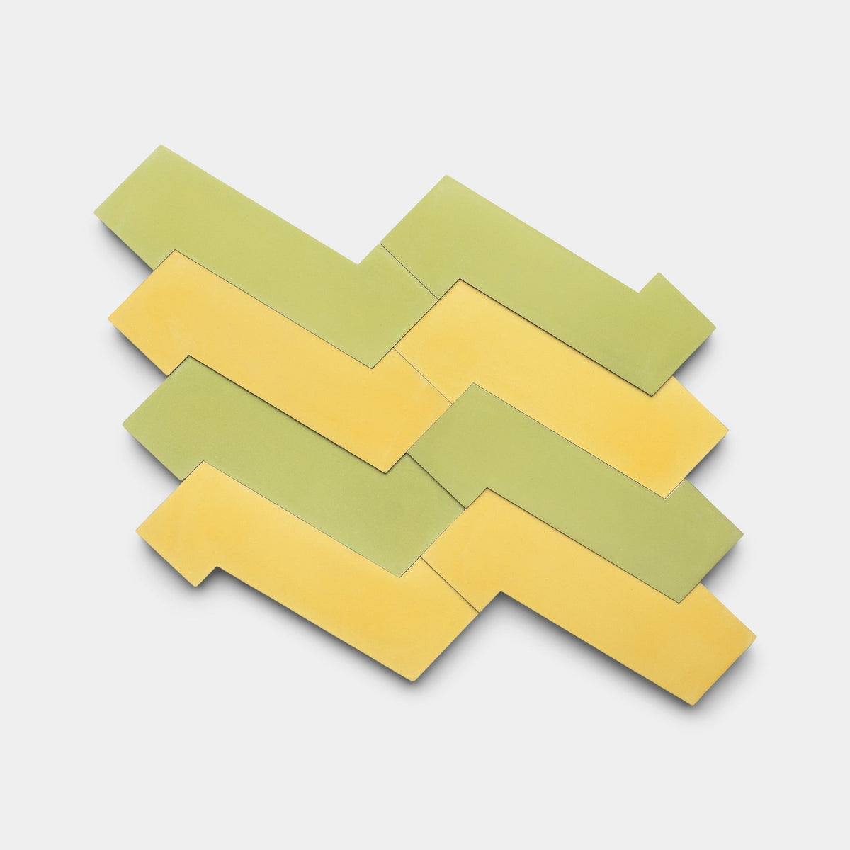 Zig Zag Lemongrass + Mustard by Zia Tile features five interlocking handmade tiles in yellow and green, arranged in a distinctive zigzag pattern on a white background, highlighting Zia Tile’s unique design style.