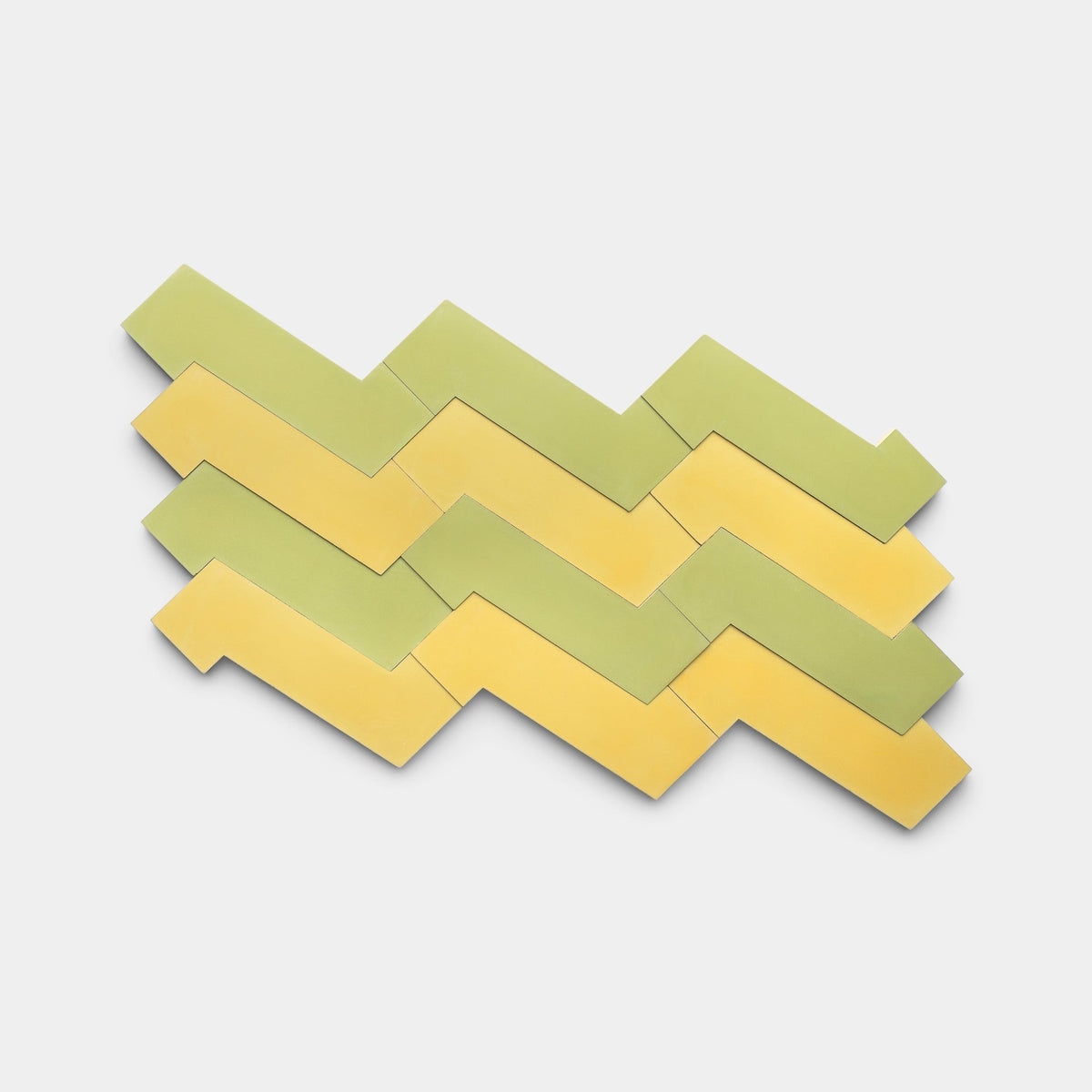 A pattern of interlocking Zig Zag Lemongrass + Mustard tiles by Zia Tile in light green and yellow on a white background.