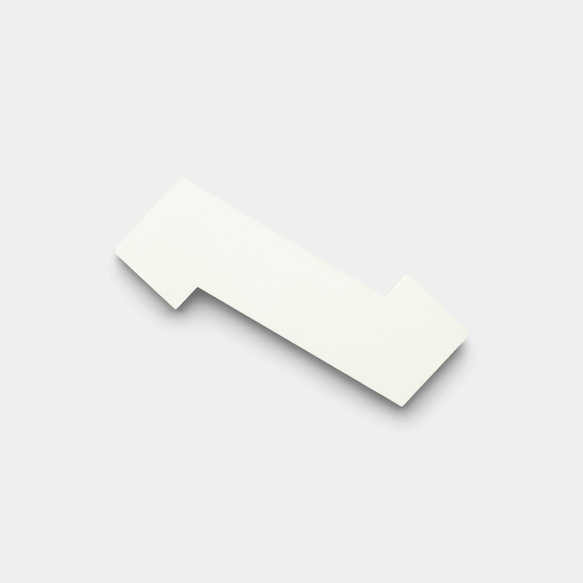 The Zig Zag White + Bone handmade tile sample by Zia Tile features a flat, white, irregular geometric shape with straight edges and right angles, displayed on a light gray background.