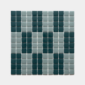 A grid of d'Orsay Vespertine + Marine Layer tiles by Zia Tile forms a geometric, face-like pattern in dark green and light grayish-blue on a light background.