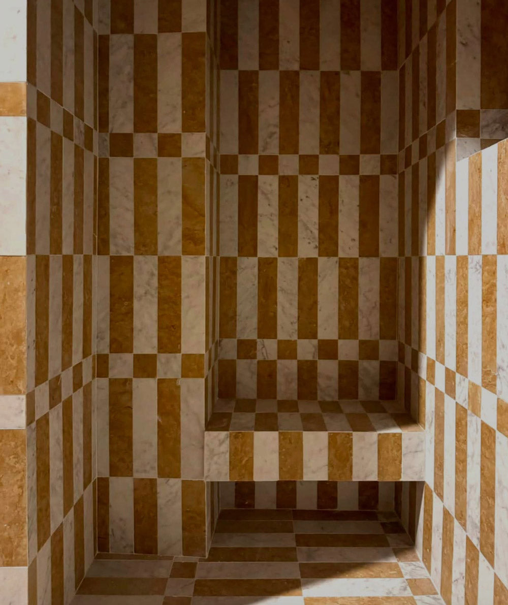 A room with a geometric pattern of alternating brown and white vertical and horizontal stripes on the walls, floor, and a built-in bench, creating an optical illusion effect.
