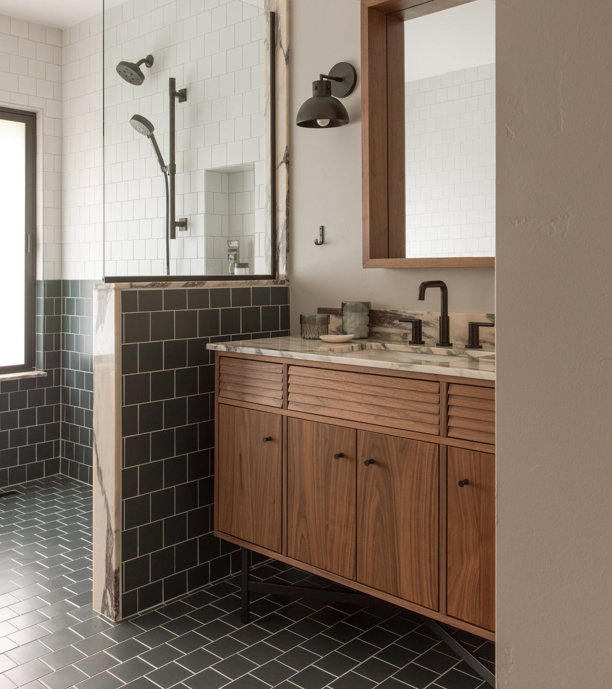 Modern bathroom features Pacific Blue 4x4 matte ceramic tile floor by Zia Tile in dark green, wood vanity with marble top, matte black fixtures, glass shower with white wall tiles, wood-framed mirror, and frosted window for natural light.